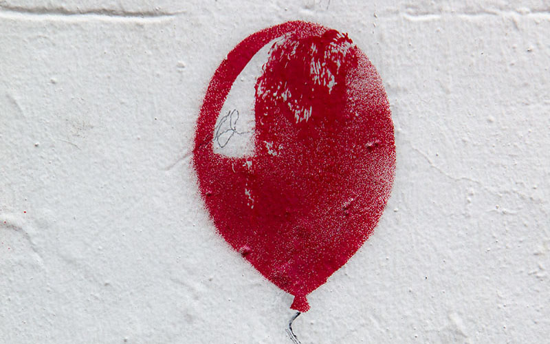 Painting of red balloon on white wall